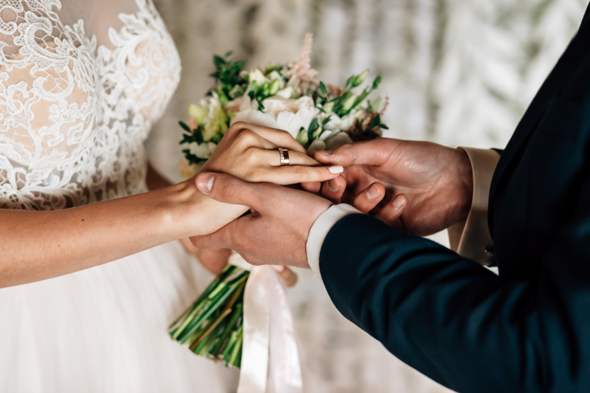 Holiday Inn Rochester-Chatham bride and groom placing ring on finger.